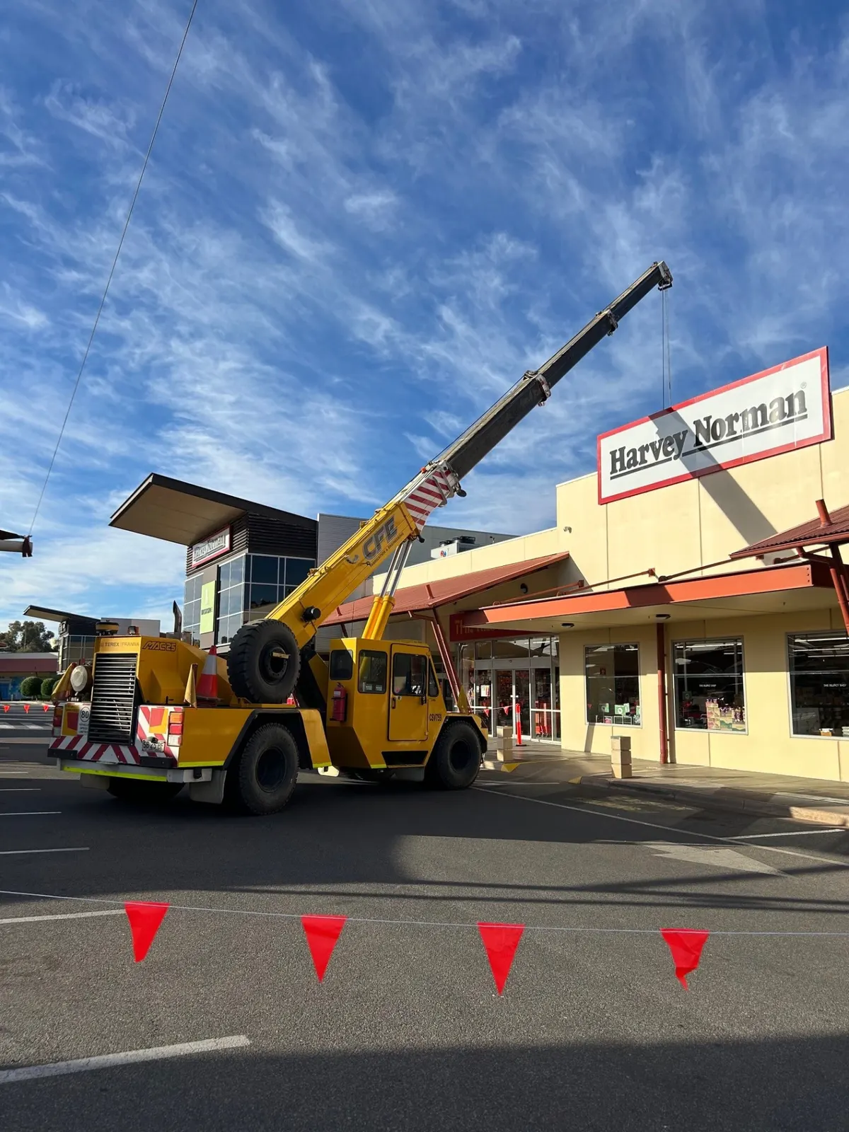 CFE mobile crane lifting signage at a retail building in Broken Hill
