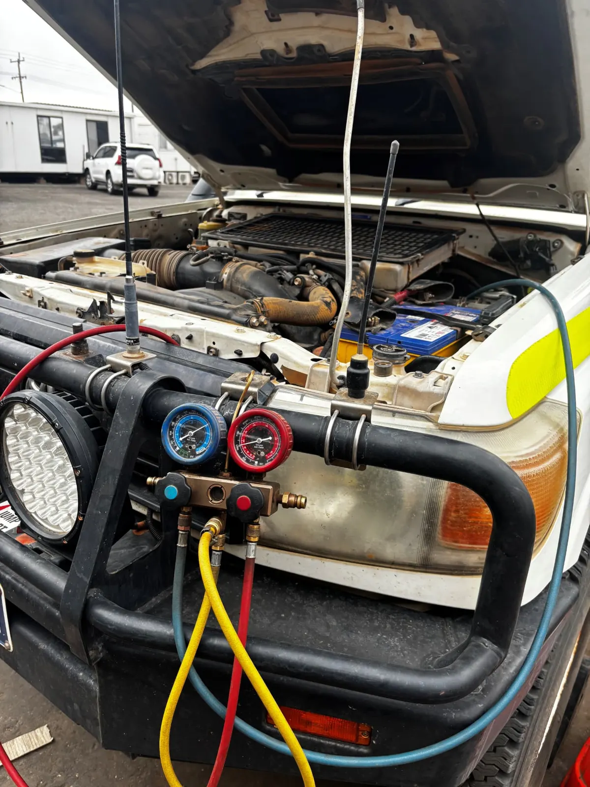 HES auto electrician using refrigerant gauges on a mine site light vehicle engine bay