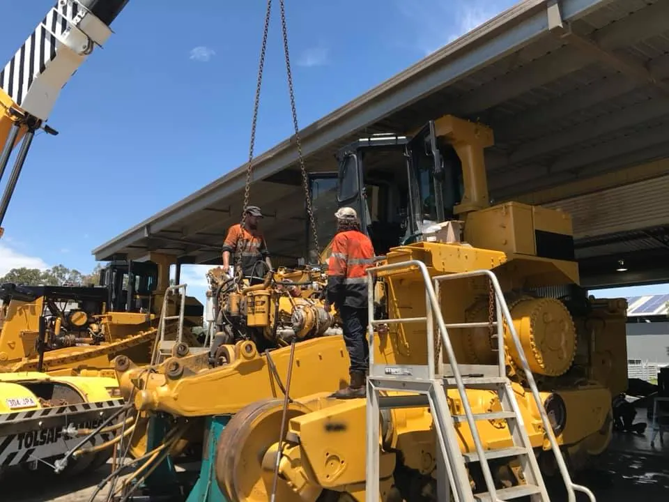 HES tradespeople craning a transmission into a dozer during a component rebuild
